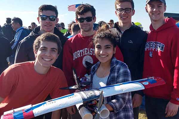 rocket club team poses holding rocket in a field