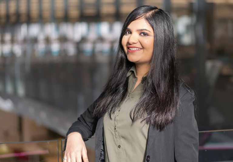 women poses with arm on railing and blurred background of building interior