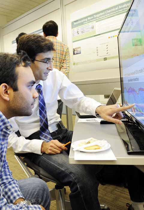 student and professor pointing to computer screen with graphs