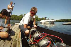 From left, team members Josh Johnson, Sylvia Talbott, and Scott Kilcoyne work on their solar-powered boat at a Charles River dock.