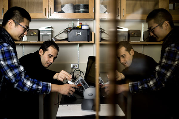 two professors working at desk with mechanical device