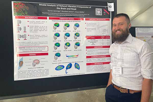 phd student standing in front of research poster smiling
